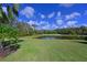 Backyard view of a grassy area with pond and golf course in the distance, surrounded by trees at 10209 Discovery Ter, Bradenton, FL 34212