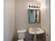 This half bath features a pedestal sink, an ornate framed mirror, neutral wall color, and a two piece toilet at 10209 Discovery Ter, Bradenton, FL 34212