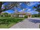 Beautiful single-story home with a tile roof, elegant columns, lush landscaping, and a paver driveway at 10209 Discovery Ter, Bradenton, FL 34212