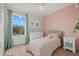 Charming bedroom with soft pink accents, featuring a cozy bed and ample natural light from the window at 12224 Longview Lake Cir, Bradenton, FL 34211