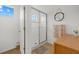 Bright tiled shower with glass doors is well lit and has an adjacent linen closet, circular mirror, and wall hanging at 12224 Longview Lake Cir, Bradenton, FL 34211