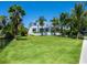 Landscaped front yard with lush lawn and tropical plants at 5910 Gulf Of Mexico Dr, Longboat Key, FL 34228