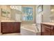 This bathroom has a marble tub, wood cabinets and dual sinks, and an abundance of natural light at 7407 Sea Island Ln, Bradenton, FL 34201