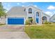 Home exterior with a vibrant blue garage door, well-kept lawn, and classic architectural details at 1228 50Th E St, Bradenton, FL 34208
