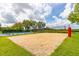 Community volleyball court with sand surface and net, surrounded by lush greenery and recreational area at 1228 50Th E St, Bradenton, FL 34208