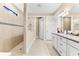 A bathroom with a walk-in shower, granite counters, double sinks, and neutral tile at 17802 Eastbrook Ter, Lakewood Ranch, FL 34202