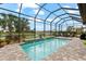 Relaxing pool area with a waterfall feature, screened enclosure, and lush landscaping at 17802 Eastbrook Ter, Lakewood Ranch, FL 34202