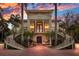 Elegant two-story home features dual grand staircases, balcony, and manicured landscaping set against a vibrant sky at 5919 Gulf Of Mexico Dr, Longboat Key, FL 34228