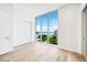 Serene bedroom offers breathtaking water views through large windows, complemented by stylish hardwood floors and modern design at 111 Golden Gate Pt # 602, Sarasota, FL 34236