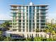 A modern condo building with floor to ceiling windows and balconies on a sunny day near the water at 111 Golden Gate Pt # 602, Sarasota, FL 34236
