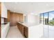 Bright, modern kitchen with wood accents, island, stainless appliances, and large windows with scenic views at 111 Golden Gate Pt # 602, Sarasota, FL 34236