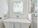 Luxurious bathroom featuring a soaking tub, modern fixtures, and a window with plantation shutters at 1516 S Orange Ave, Sarasota, FL 34239