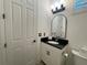 Powder room featuring a dark granite vanity, modern mirror, and white cabinets at 15618 Castle Park Ter, Lakewood Ranch, FL 34202