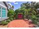 Landscaped garden with a red swing and brick-paved patio area at 1775 Southwood St, Sarasota, FL 34231