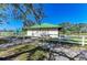 Charming exterior featuring a green metal roof, white fence, and accessible entrance, set amidst lush greenery at 6205 Triple Tail Ct # 101, Lakewood Ranch, FL 34202