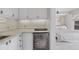 Small kitchenette with white cabinets, marble counters, and mini-fridge at 75 Osprey Point Dr, Osprey, FL 34229