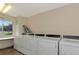 Bright laundry room featuring multiple commercial-grade washing machines and dryers, plus a window with a view at 1540 Glen Oaks E Dr # B336, Sarasota, FL 34232