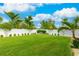 Spacious backyard with lush lawn, white fence, and tropical landscaping at 4817 Sarasota Ave, Sarasota, FL 34234