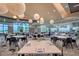 Large clubhouse dining area with multiple tables, place settings, stylish chairs, pendant lighting, and scenic views at 15625 San Lazzaro Ave, Bradenton, FL 34211
