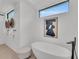 Modern bathroom featuring a soaking tub, an abstract art piece, and a geometric window at 2038 Datura St, Sarasota, FL 34239