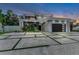 Modern two-story home featuring a black garage door, a balcony, and lush landscaping at dusk at 2038 Datura St, Sarasota, FL 34239