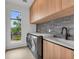 Well-equipped laundry room with wood cabinets, modern washer and dryer, and a sink at 2038 Datura St, Sarasota, FL 34239