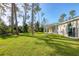 Back exterior view of the house showcasing a covered patio and grassy yard at 2814 Daphne Rd, North Port, FL 34288
