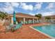 Community pool with lounge chairs, tables, and umbrellas at 4523 Cinnamon Dr # 2702, Sarasota, FL 34238