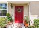Red front door accented by potted plants and a spring wreath at 8256 Enclave Way # 101, Sarasota, FL 34243