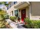 Charming front entry features a red door, lush landscaping, and a welcoming walkway at 8256 Enclave Way # 101, Sarasota, FL 34243