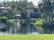 Peaceful pond-side view of condo building, lush greenery, and palm trees at 6447 Egret Ln # 413, Bradenton, FL 34210