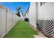 Narrow backyard with artificial turf, white fence, and garden accents at 1521 Siesta Dr, Sarasota, FL 34239