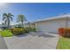 Charming villa with well-manicured lawn, flowering bushes, palm trees, a driveway, and a two-car garage at 5395 Christie Ann Pl # 9, Sarasota, FL 34233