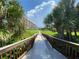 Wooden walkway to the beach lined with lush tropical landscaping at 5740 Midnight Pass Rd # 506F, Sarasota, FL 34242