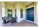 Covered front porch with two wicker chairs and a blue front door at 1049 River Wind Cir, Bradenton, FL 34212