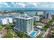 Stunning aerial view of a modern condo building with a rooftop terrace and pool, near a marina and waterfront at 111 Golden Gate Pt # 402, Sarasota, FL 34236