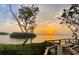 Scenic sunset view from a wooden deck overlooking calm water and lush vegetation at 1508 Pelican Cove Rd # Gr233, Sarasota, FL 34231
