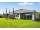 Spacious backyard featuring healthy lawn, young palm trees, and screened-in lanai at 16112 Isola Pl, Bradenton, FL 34211