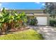 Tan house with white garage door and lush tropical landscaping at 1742 Adams S Cir, Largo, FL 33771