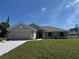 Charming single-story home featuring a two-car garage, well-manicured lawn, and blue shutters at 4744 Badali Rd, North Port, FL 34286