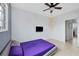 Bedroom with purple bedding, wall-mounted TV and an ensuite bathroom at 4990 Baraldi Cir # 211, Sarasota, FL 34235