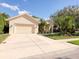 Tan house with a two-car garage and lush landscaping at 8047 Desoto Woods Dr, Sarasota, FL 34243