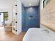 Bathroom with blue tile shower, freestanding bathtub, and light wood floors at 1331 Quail Dr, Sarasota, FL 34231