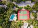 Aerial view of a community pool and tennis courts surrounded by lush greenery and mature trees at 1519 Pelican Point Dr # 292, Sarasota, FL 34231