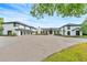 Stunning white home with black trim, multi-car garage, circular driveway, and manicured landscaping at 2410 Slough Rd, Sarasota, FL 34240