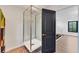 Modern bathroom showcasing a luxury glass shower with metal frame and a black door leading to the hallway at 2410 Slough Rd, Sarasota, FL 34240