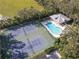 Aerial view of the community pool, clubhouse, and tennis courts, surrounded by lush greenery and mature trees at 2603 River Woods Dr, Parrish, FL 34219