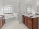 Bathroom showcasing dark wood cabinets, white tile floors, a standalone shower, and a soaking tub under a window at 2603 River Woods Dr, Parrish, FL 34219