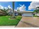 House exterior with gray walls, white garage door, and a palm tree in the front at 316 Roseling Cir, Venice, FL 34293