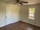 Bright bedroom featuring dark wood floors, vertical wood paneling, ceiling fan, and window at 1936 E 30Th Ave, Bradenton, FL 34208